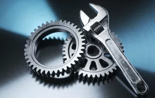 金属质感齿轮与扳手组合，蓝灰色渐变背景，展现工业制造精密感