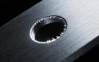 微距摄影风格的不锈钢冲孔毛边特写，清晰展示了毛边的具体形态和尺寸