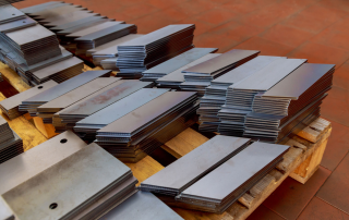 整齐堆放在木质托盘上的激光切割金属成品板材，展示工业生产中的批量交付成果