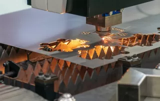 展示车间内激光切割设备正在进行钣金加工的场景，火花四溅，体现工业生产的精密与力量感