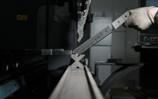 展示金属折弯加工的真实操作过程，工人正在将金属板材放置到折弯机上