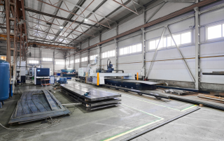 宽敞明亮的现代化钣金加工车间，展示自动化生产线和智能监控系统，工人在有序操作