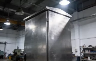 呈现完整的电控柜外观与锌处理后的金属质感，背景为现代化车间环境，体现批量生产后的工艺精度与工业美感。