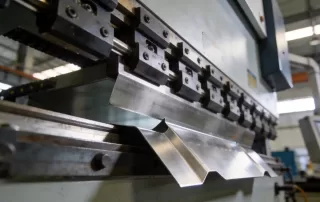 数控折弯机正在加工新能源储能柜侧板，低角度拍摄突出机床的工业美感和精密结构，背景为现代化车间环境，光线柔和，展示高精度金属异形折弯工艺